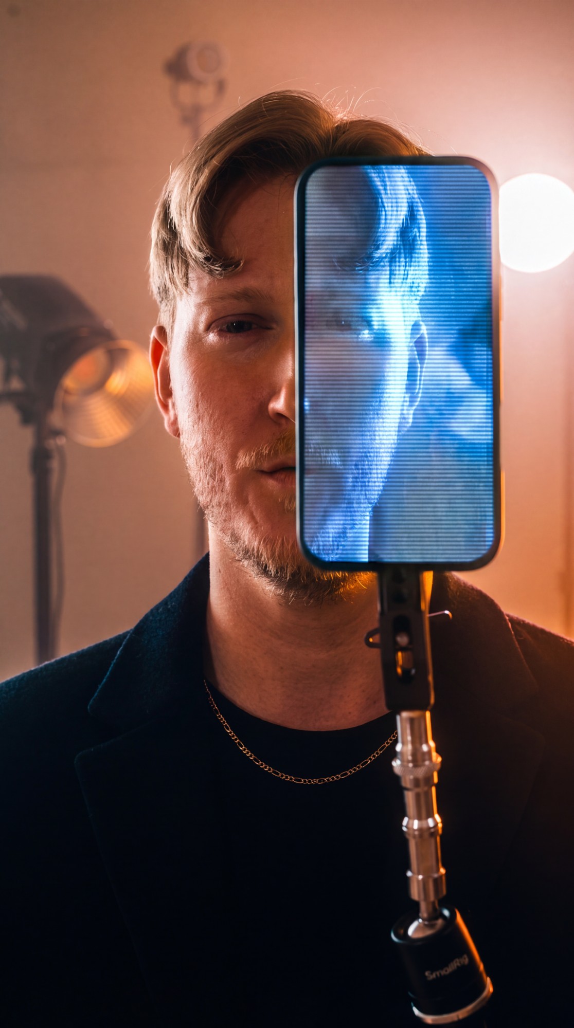 Ryan Xander in warm studio light, with a blue image of his face on a phone screen